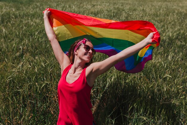 Mujer Que Sostiene La Bandera Gay Del Arco Iris En Un Prado Verde Al