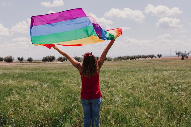 Mujer Que Sostiene La Bandera Gay Del Arco Iris En Un Prado Verde Al