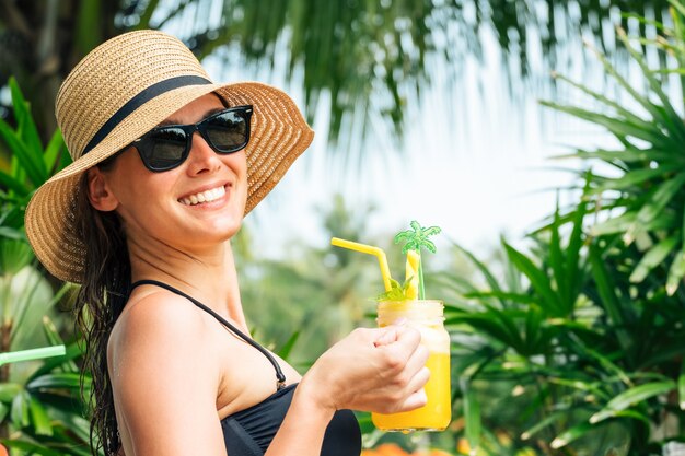 Mujer relajada en bikini bebiendo cóctel de piña Foto Premium