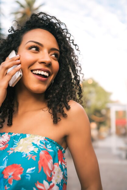 Retrato de joven mujer latina afroamericana hablando por teléfono al