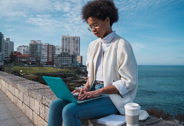 Retrato de joven mujer latina usando su computadora portátil mientras