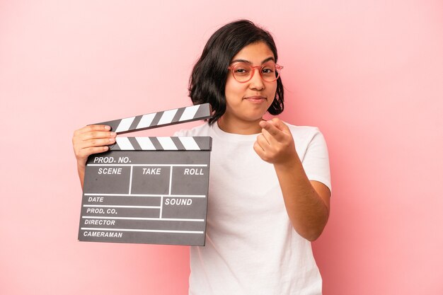 Jovem Mulher Latina Segurando Claquete Isolada No Fundo Rosa Apontando