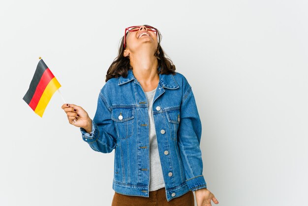 Jovem mulher latina segurando uma bandeira alemã isolada na parede