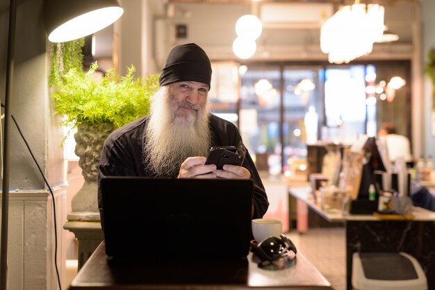 Premium Photo Mature Bearded Hipster Man Using Phone And Laptop At