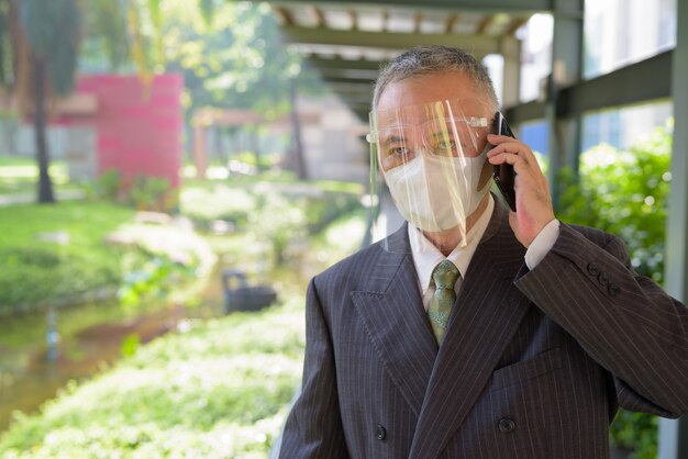 Premium Photo Mature Japanese Businessman With Mask And Face Shield