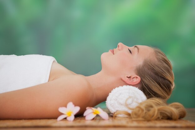 Premium Photo Peaceful Blonde Lying On Bamboo Mat With Flowers