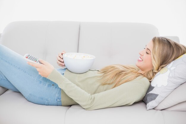 Premium Photo Pretty Blonde Holding Popcorn Lying On Cosy Sofa