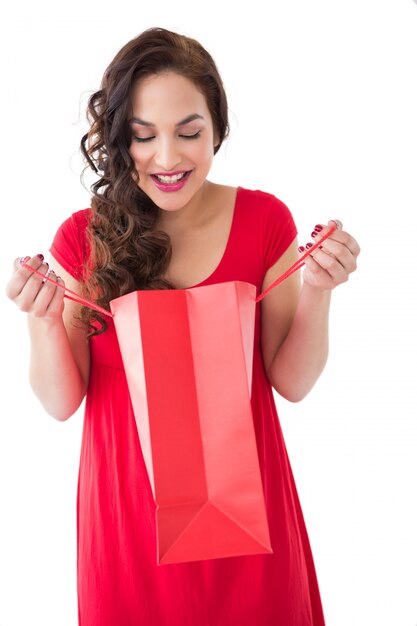 Premium Photo Stylish Brunette In Red Dress Opening Gift Bag On White