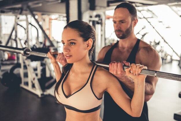 Atrakcyjna dziewczyna sportowa pracuje obecnie ze sztangą w siłowni. Premium Zdjęcia