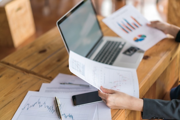 Biznes kobieta strony z finansowych wykresów i laptopa na stole. Darmowe Zdjęcia Biznes kobieta strony z finansowych wykresów i laptopa na stole. Darmowe Zdjęcia