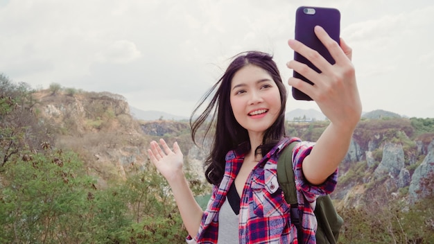 Blogger asian backpacker kobieta nagrywa wideo vlog na szczycie góry, młoda kobieta szczęśliwa przy użyciu telefonu komórkowego sprawia, że vlog video cieszy się wakacjami na wędrówce. Darmowe Zdjęcia