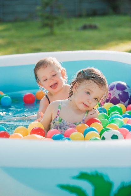 Dwie Małe Dziewczynki Bawiące Się Zabawkami W Nadmuchiwanym Basenie W Słoneczny Letni Dzień