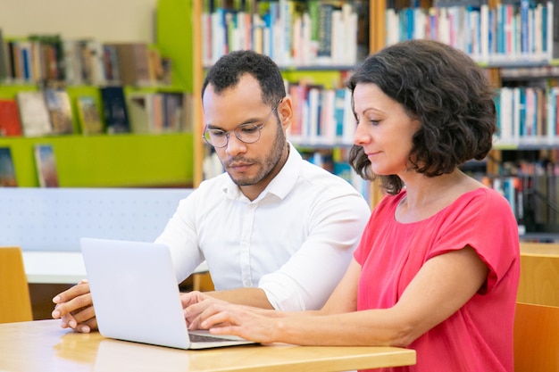 Dwóch dorosłych studentów współpracujących przy projekcie w bibliotece Darmowe Zdjęcia