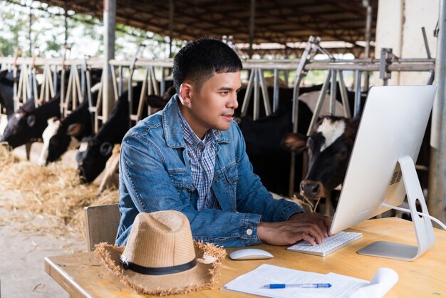 Farmer używa komputera do informacji o gospodarstwie. aby sprzedawać mleko online Premium Zdjęcia