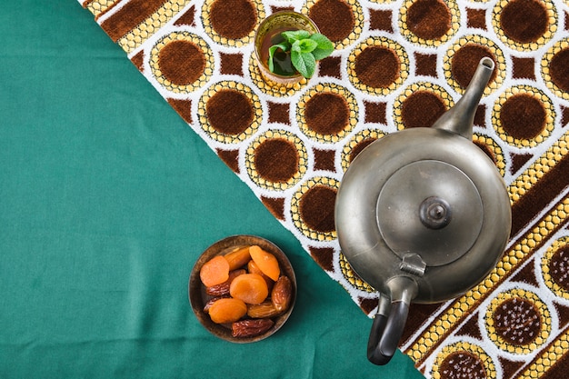 Filiżanka blisko retro teapot i wysuszonych owoc blisko matuje na marszczącym materiale Darmowe Zdjęcia
