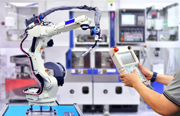 Inżynier sprawdza i kontroluje automatyzację pomarańczowy nowoczesny system robotów w fabryce, robot przemysłowy. Premium Zdjęcia