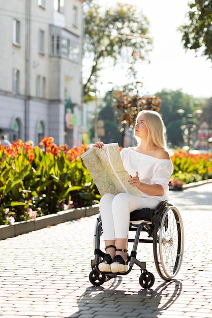 Kobieta Na Wózku Inwalidzkim Patrząc Na Mapę Na Zewnątrz Darmowe Zdjęcie
