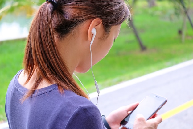 Kobieta Obserwująca Ją W Smartfonie Do Wyboru Muzyki Przed ćwiczeniami. Premium Zdjęcia