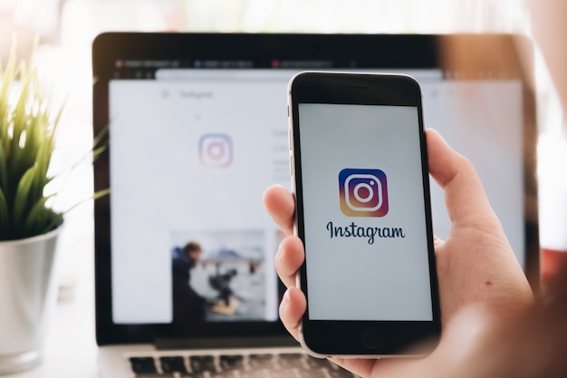 Kobieta trzyma iphone'a 6s z aplikacją instagram na ekranie kawiarni. instagram to aplikacja do udostępniania zdjęć na smartfony Premium Zdjęcia