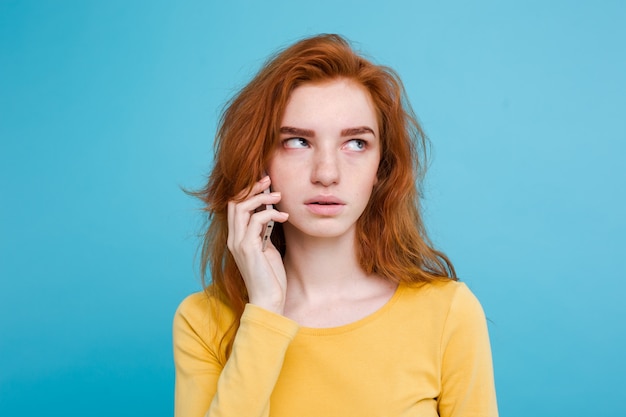 Koncepcja stylu życia - portret imbir czerwone włosy dziewczyna z szokujące i stresujące wypowiedzi podczas rozmowy z przyjacielem przez telefon komórkowy. pojedynczo na niebieskim tle pastelowe. skopiuj miejsce. Darmowe Zdjęcia
