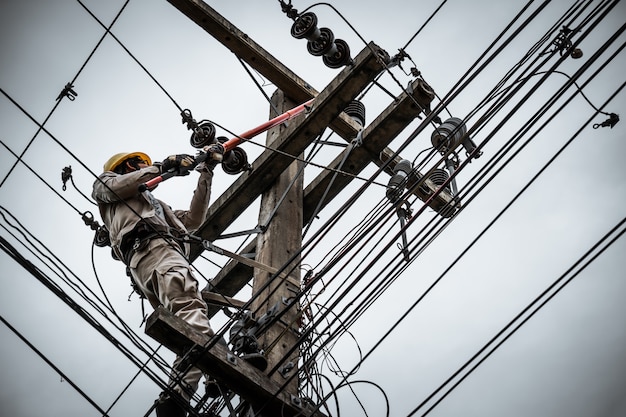 Lineman używa zacisku do odłączenia kabla w celu naprawy uszkodzonego wyłącznika bezpiecznika. Premium Zdjęcia