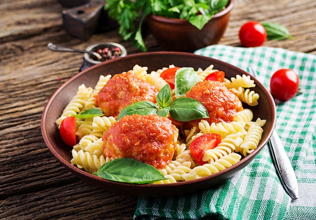 Makaron fusilli z klopsikami w sosie pomidorowym i bazylią w misce, kuchnia włoska. Premium Zdjęcia
