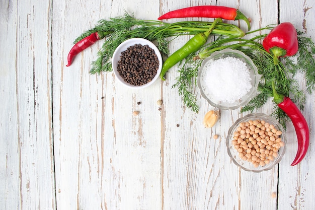 Marynaty na biały drewniany stół z zieloną i czerwoną i papryką chili, kopru włoskiego, soli, czarnego pieprzu, czosnku, grochu, z bliska, zdrowe pojęcie, widok z góry, płaskie świeckich Darmowe Zdjęcia