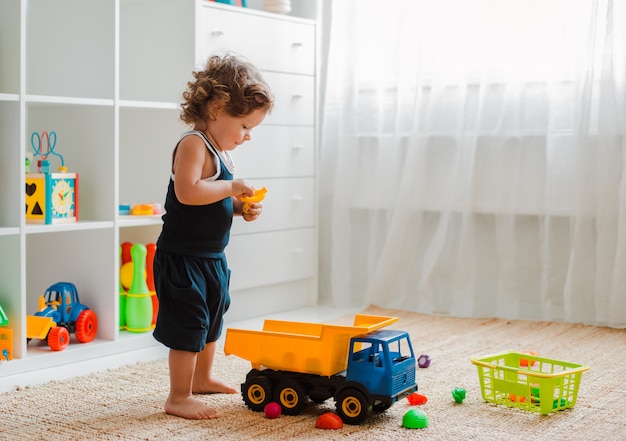 Matka i dziecko bawią się na podłodze w pokoju dziecinnym. mama i mały chłopiec robią z plastikowymi kolorowymi zabawkami. Premium Zdjęcia