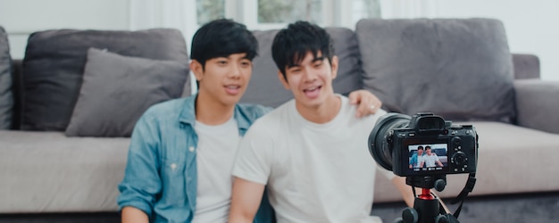 Młoda azjatycka para gejów influencer para vlog w domu. nastoletni koreańscy mężczyźni lgbtq szczęśliwi relaksują się przy użyciu kamery zapisującej vlog wideo w mediach społecznościowych, leżąc na kanapie w salonie w domu. Darmowe Zdjęcia