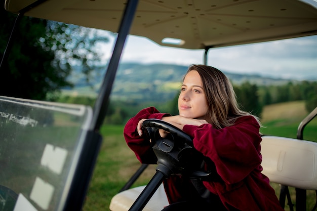 Młoda Kobieta Bawić Się Z Golfowym Buggy Samochodem Na Polu W Górach Premium Zdjęcia
