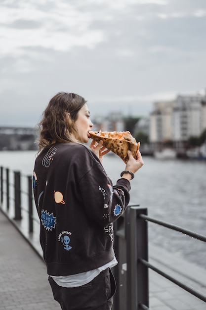 Młoda piękna kobieta je plasterek pizza na miasto ulicie Darmowe Zdjęcia