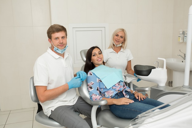 Młody męski dentysta i szczęśliwa żeńska pacjentka. scena życia biuro dentysta. praktyka lekarska. opieka zdrowotna nad pacjentem Premium Zdjęcia