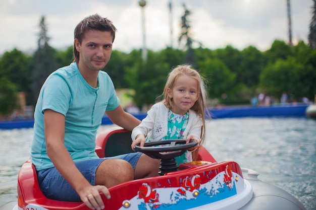 Młody tata i jego mała dziewczynka jeżdżą na łodzi w atrakcji Premium Zdjęcia