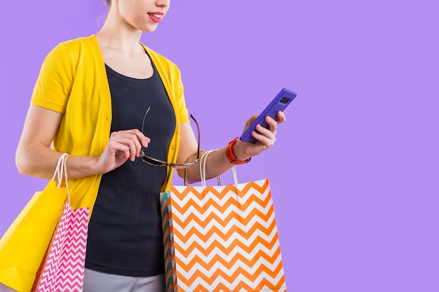 Modna kobieta używa telefon komórkowego z trzymać kolorową papierową torbę i eyeglasses Darmowe Zdjęcia