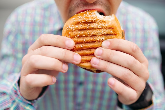 Nie Do Poznania Człowiek Jedzenie Pysznego Hamburgera Z Grillowanym Chlebem Premium Zdjęcia