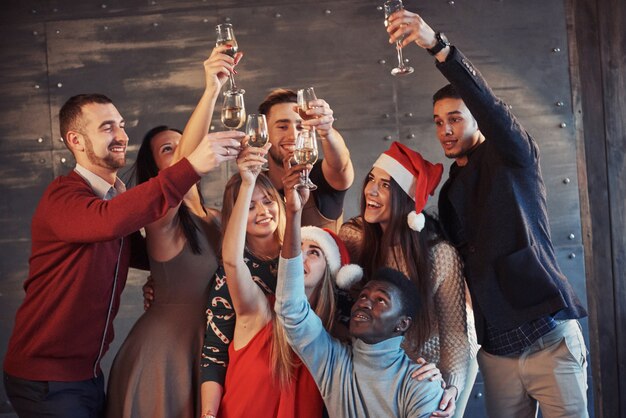 Nowy rok się zbliża! grupa rozochoceni młodzi wieloetniczni ludzie w santa kapeluszach na przyjęciu, pozuje emocjonalnego stylu życia pojęcia ludzi Premium Zdjęcia