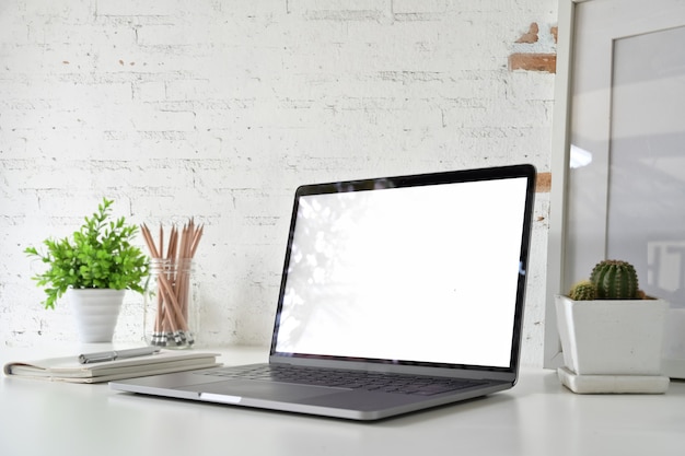 Obszar roboczy z pustym białym ekranie laptopa na poddaszu biurko. Premium Zdjęcia