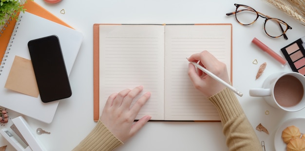 Odgórny Widok Młody żeński Writing Na Pustym Notatniku W Ciepłym Beżowym Kobiecym Workspace Pojęciu Z Uzupełniał Premium Zdjęcia