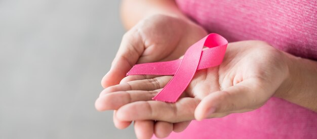 Październikowy miesiąc świadomości raka piersi, kobieta w różowej koszulce z ręką trzymającą różową wstążkę do wspierania osób żyjących i chorych. opieka zdrowotna, międzynarodowy dzień kobiet i światowy dzień walki z rakiem Premium Zdjęcia