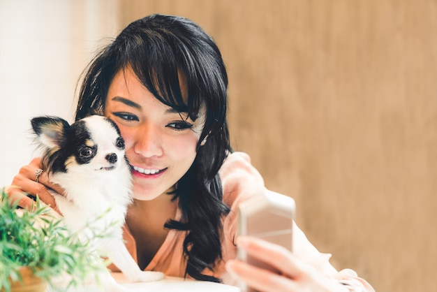 Piękna azjatycka kobieta bierze selfie z ślicznym chihuahua psem w domu Premium Zdjęcia