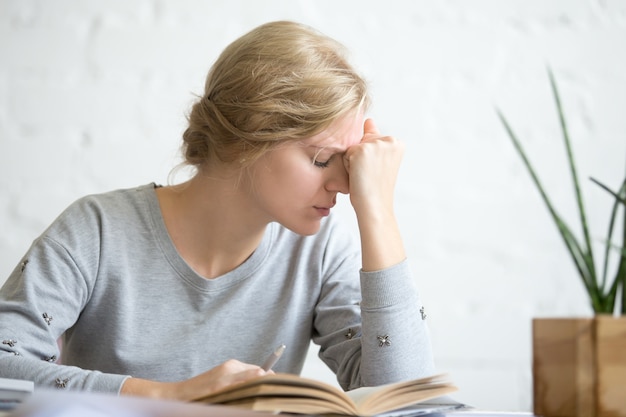 Portret młodego przepracowany student dziewczyny siedzącej przy stole Darmowe Zdjęcia