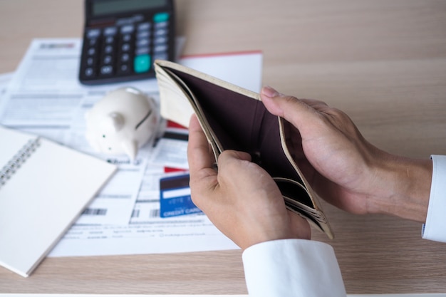 Ręce otwierają pustą torebkę po obliczeniu kosztu z karty kredytowej i rachunku Premium Zdjęcia