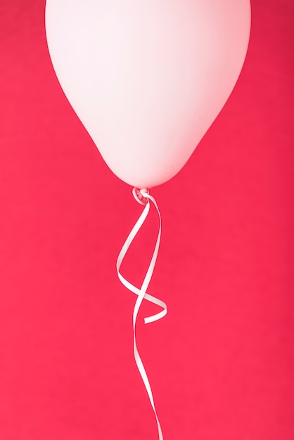 Różowy balon ze wstążką na czerwonym tle Darmowe Zdjęcia