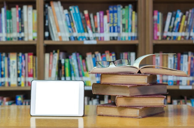 Stara książka na biurku w bibliotece z tabletu i okulary Premium Zdjęcia