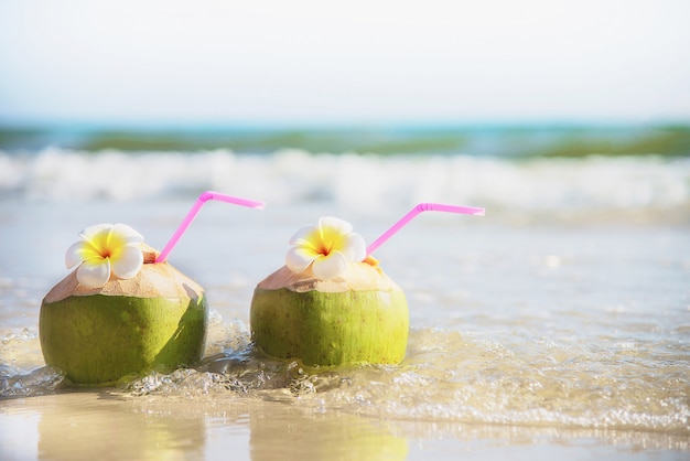 Świeży kokos z kwiatem plumeria urządzone na czystej, piaszczystej plaży z fal morskich - świeże owoce z koncepcją wakacje piasek morze słońce Darmowe Zdjęcia