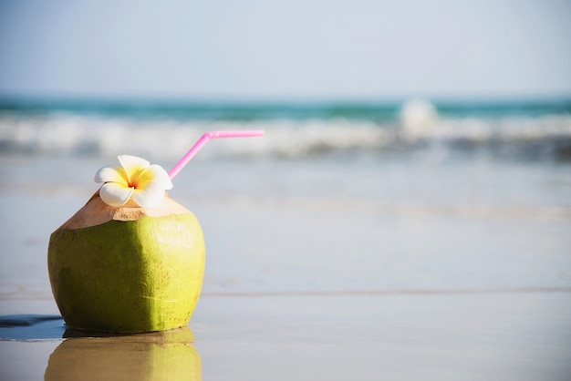 Świeży kokos z kwiatem plumeria urządzone na czystej, piaszczystej plaży z fal morskich - świeże owoce z koncepcją wakacje piasek morze słońce Darmowe Zdjęcia