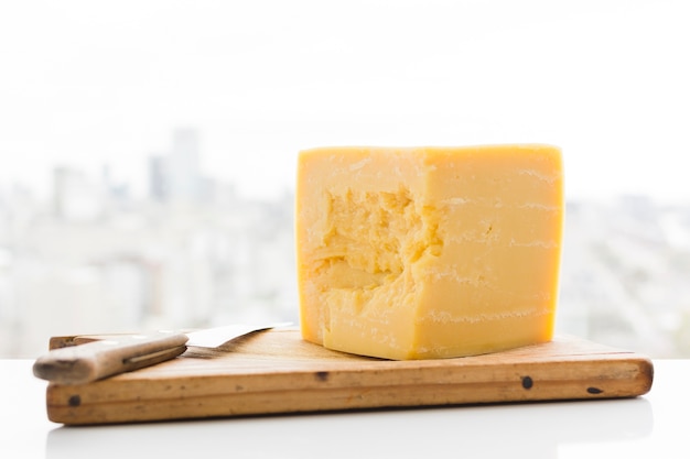 Sześcian Sera Cheddar Z Nożem Na Desce Do Krojenia Nad Biurkiem Darmowe Zdjęcia