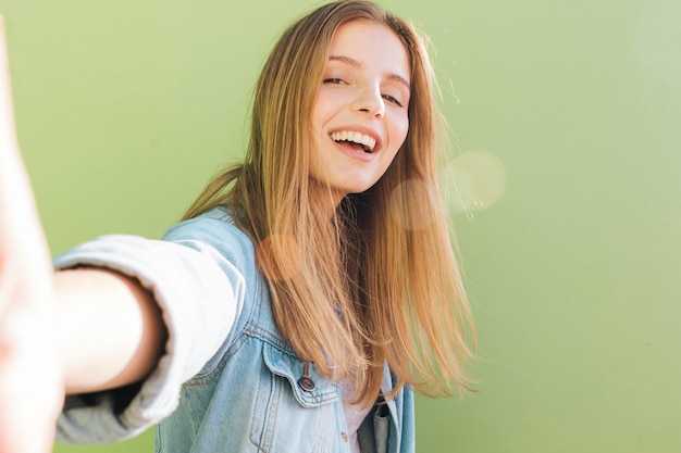 Uśmiechnięta blondynki młoda kobieta bierze selfie przeciw mennicy zieleni tłu Darmowe Zdjęcia