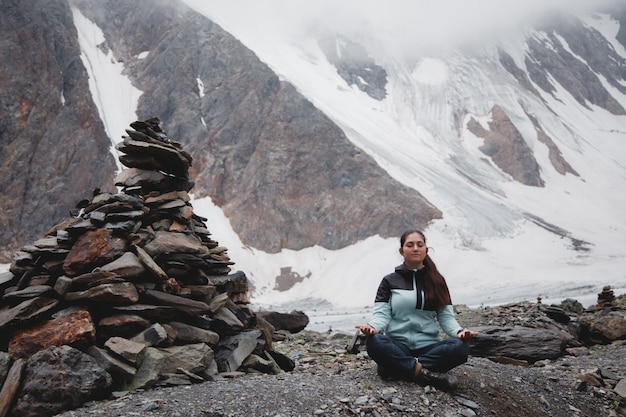 Wewnętrzny spokój i troska. kobieta medytuje z pięknym widokiem na ośnieżone góry. aktru glacier highlands Premium Zdjęcia