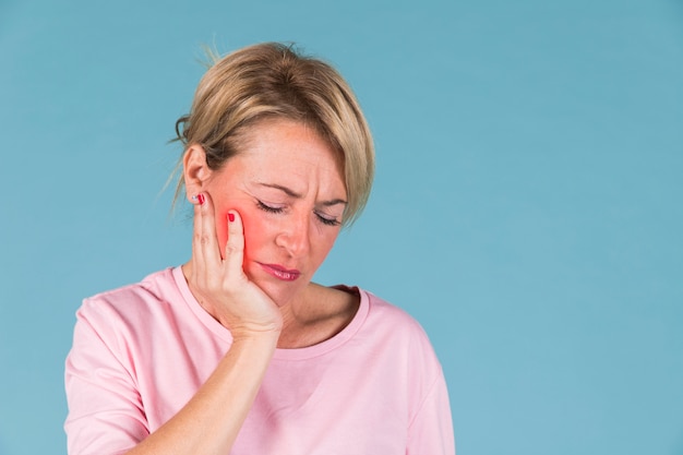 Zakończenie chora kobieta ma toothache przed błękitnym tłem Darmowe Zdjęcia Zakończenie chora kobieta ma toothache przed błękitnym tłem Darmowe Zdjęcia